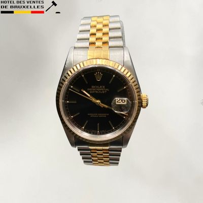 une montre Rolex noire et dorée montée sur un bracelet argenté et doré