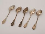 six silver spoons are lined up in a row on a white surface