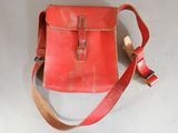 an old red leather bag with a strap on a white surface