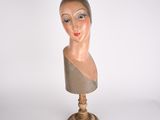 une tête de mannequin posée sur un socle en bois, sur fond blanc