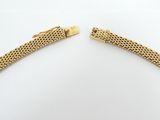 a close up of two gold bracelets on a white surface