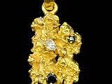 a close up of a gold pendant with a black and pink stone