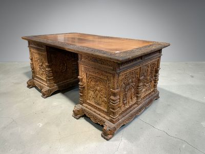 un vieux bureau en bois dont le plateau est orné de sculptures
