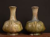 two vases sitting on a table with a black background