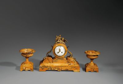 une petite horloge et deux petites bougies posées sur une table