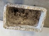 a cement planter with dirt in it on a table