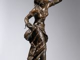a bronze statue of a woman holding a basket on top of a rock
