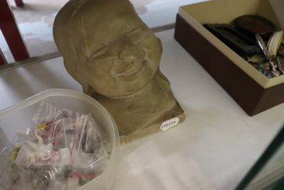 une statue représentant un homme assis sur une table, à côté d'une boîte de bonbons