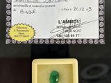 a green jade stone in a yellow box with a certificate