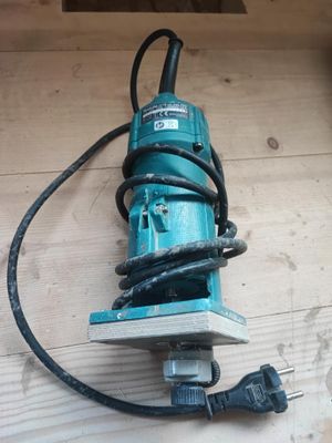 une perceuse électrique posée sur un parquet, avec son cordon d'alimentation