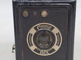 a small black camera with a gold button on it