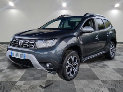 La Dacia grise est garée dans une grande pièce au sol carrelé en damier.