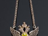 a silver necklace with a yellow and black emblem on it
