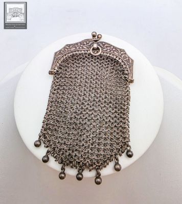 un gros plan d'un sac à main en cotte de mailles posé sur un gâteau blanc