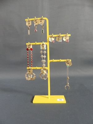 un présentoir à bijoux jaune sur lequel sont disposées plusieurs paires de boucles d'oreilles
