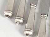 six silver plated knives with silver handles on a white surface