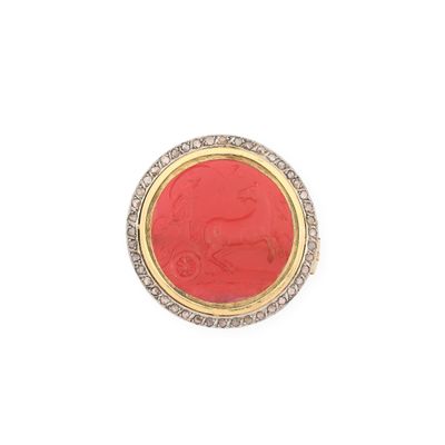 un gros plan d'une bague rouge et dorée sur fond blanc