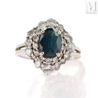 a close up of a diamond and sapphire ring on a white surface