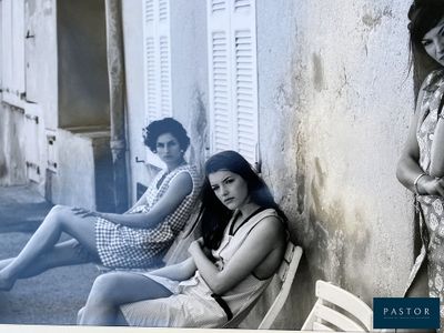 two women sitting on a bench in front of a building