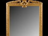an ornately carved mirror with a gold frame on a white surface