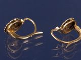 pair of gold earrings with black stones on a blue surface
