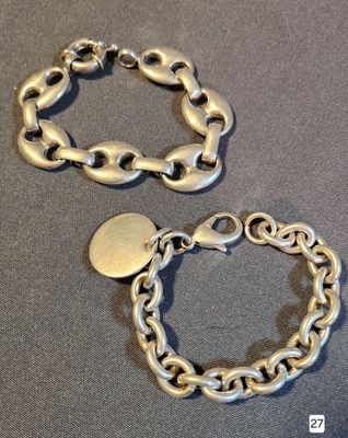 two pieces of silver bracelets on a table