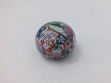 a small glass ball with a design on it on a white surface