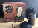 La cafetière est posée sur une table, à côté d'une boîte de café.