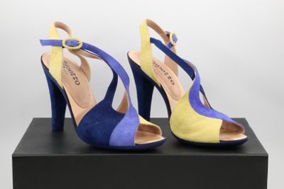 a pair of blue and yellow high heels on a black box