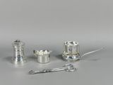 three silver objects on a table with a spoon and spoon rest