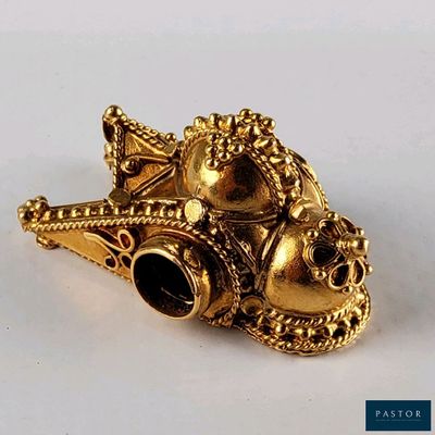une broche dorée posée sur une surface blanche