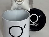 une montre posée dans une tasse à café à côté d'un coffret à montres