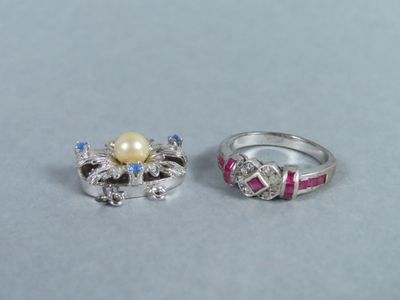 two rings with diamonds and a pearl on a blue surface