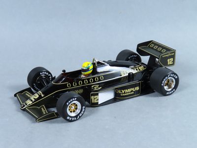 la maquette d'une voiture de course noire et dorée posée sur une surface blanche