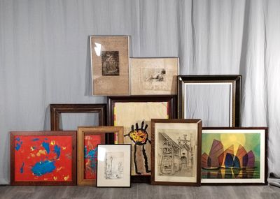 de nombreux tableaux encadrés posés par terre, à côté d'un rideau