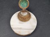 an image of a gold and green ring sitting on top of a marble base