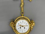 a gold clock hanging on the wall with a cross on it
