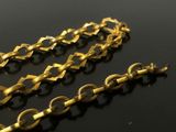 two gold chains on a black surface with a black background