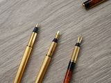three pens are lined up next to each other on a wooden table