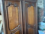 a man that is sitting in front of a wooden armoire