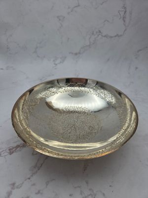 an antique silver plate on a marble table with a white background