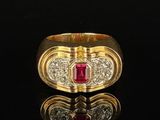 a close up of a gold ring with a ruby stone and diamonds