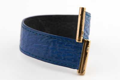 bracelet en cuir bleu avec un fermoir doré sur fond blanc