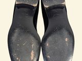 pair of black leather shoes with holes on them on a white surface
