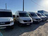 Plusieurs fourgonnettes blanches sont garées en rangée sur un parking