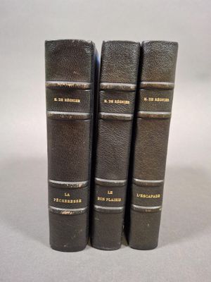 trois vieux livres sont alignés sur une surface blanche