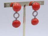 pair of coral and diamond earrings on a silver stand