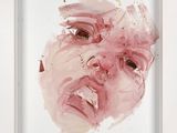tableau représentant le visage d'une femme dans un cadre blanc accroché à un mur blanc