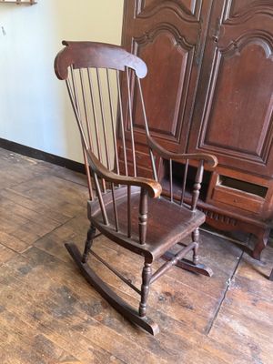 a rocking chair in the corner of a room next to a cabinet