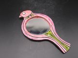 un miroir en forme d'oiseau rose et vert posé sur une table noire